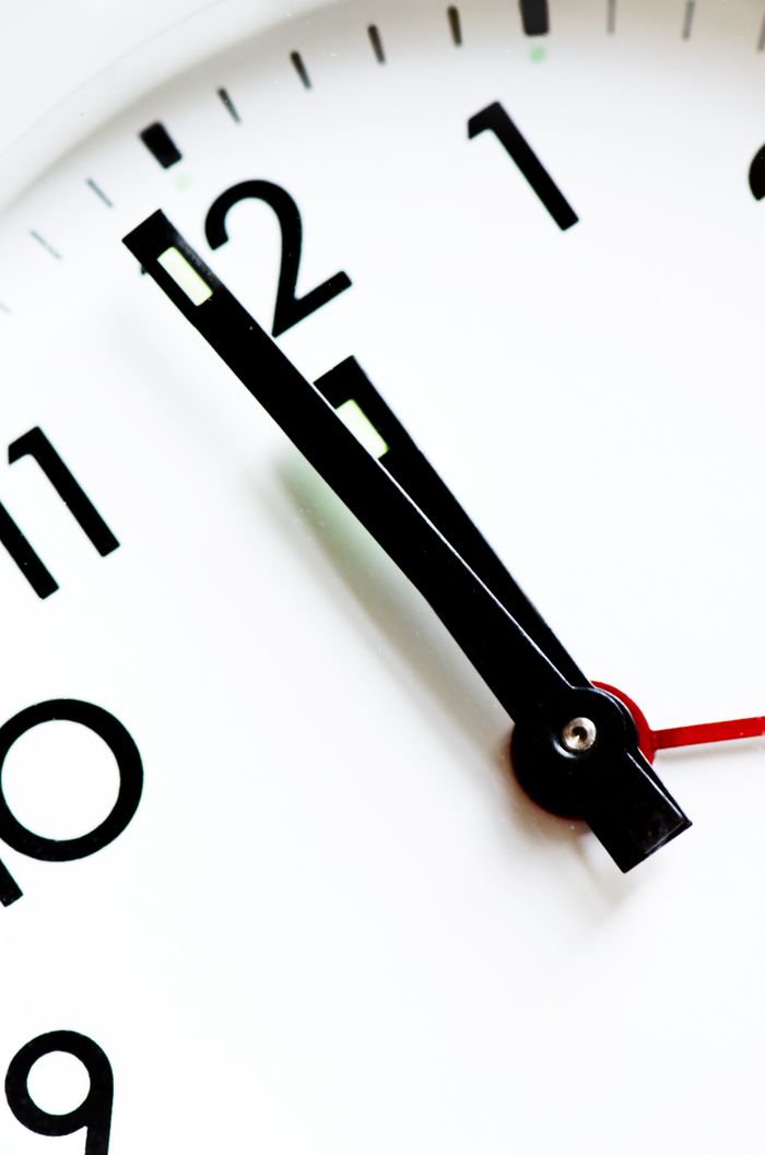 services-01 Detailed view of a black and white analog clock face with hands pointing near twelve.